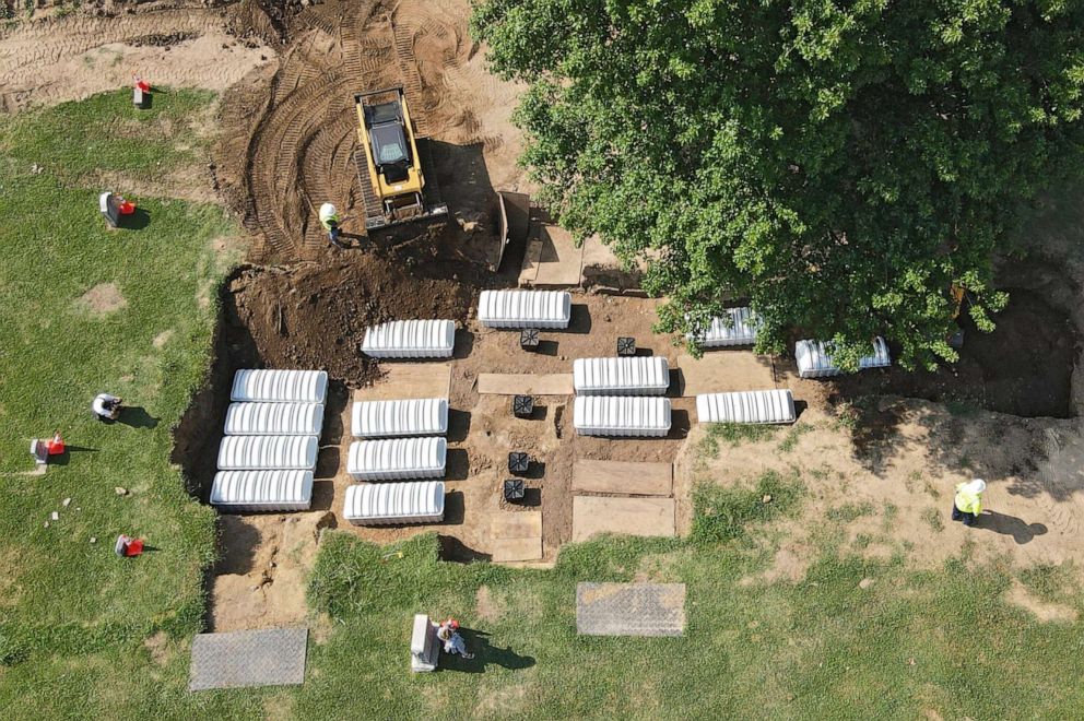 PHOTO: A mass grave is re-filled with dirt after a small ceremony at Oaklawn Cemetery in Tulsa, Okla., July 30, 2021.
