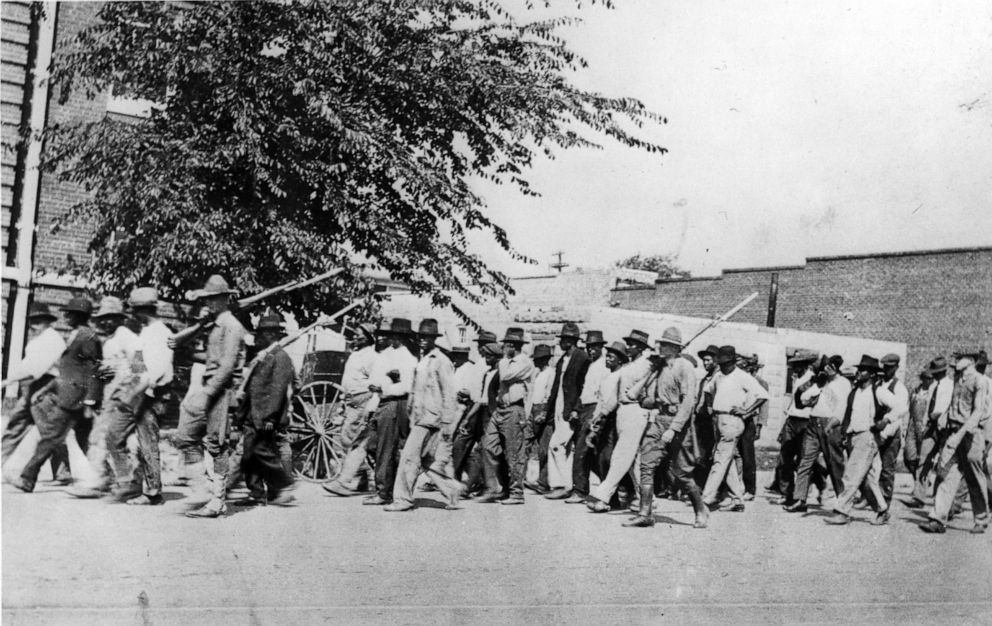 PHOTO: Photograph of a group of National Guard Troops who are carrying rifles with bayonets attached while escorting unarmed African American men after the Tulsa Race Massacre, Tulsa, Okla., 1921.