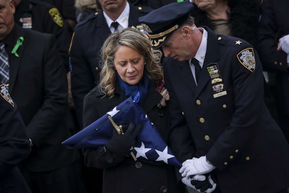 PHOTO: Leanne Simonsen, wife of fallen NYPD Detective Brian Simonsen, receives a flag after her late husband's remains were carried out of the church following his funeral service at the Church of St. Rosalie, Feb. 20, 2019, in Hampton Bays, N.Y.