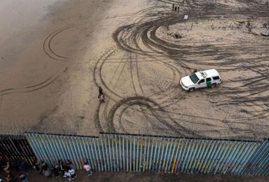 PHOTO: An aerial view of migrants who form part of the Central American migrant caravan being detained and escorted by a border patrol agent after crossing the US-Mexico border fence in Playas de Tijuana, Baja California state, Mexico, Dec. 9, 2018.
