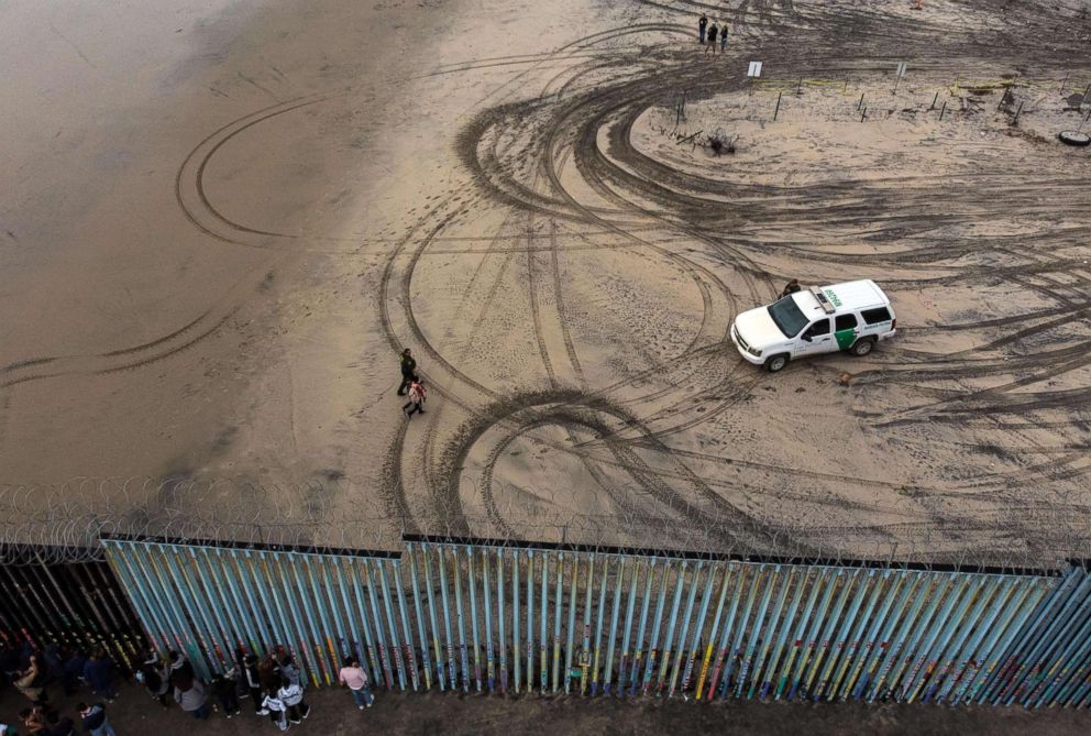 PHOTO: An aerial view of migrants who form part of the Central American migrant caravan being detained and escorted by a border patrol agent after crossing the US-Mexico border fence in Playas de Tijuana, Baja California state, Mexico, Dec. 9, 2018. 