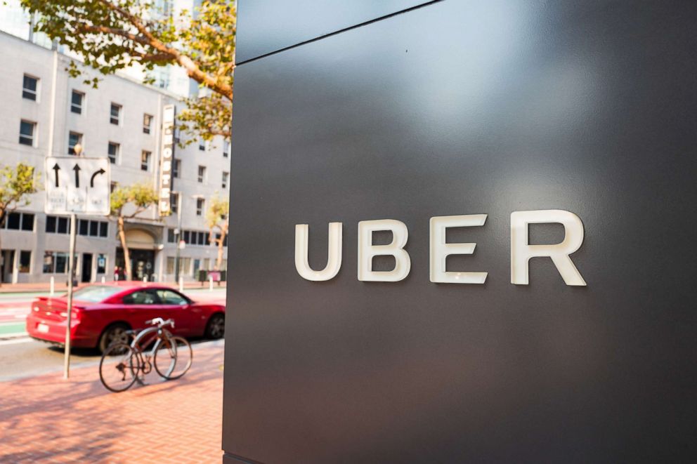 PHOTO: Sign with logo at the headquarters of car-sharing technology company Uber in the South of Market (SoMa) neighborhood of San Francisco, with red vehicle visible in the background parked on Market Street, Oct. 13, 2017. 