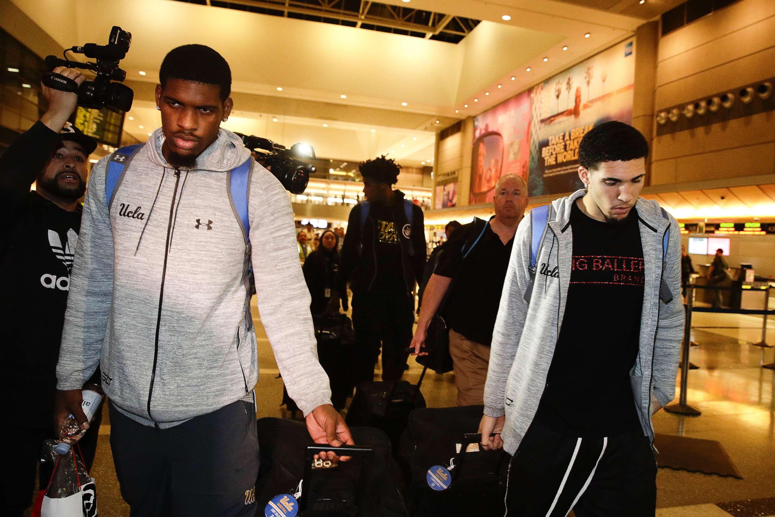 PHOTO: UCLA basketball players Cody Riley, left, LiAngelo Ball, right, and Jalen Hill, background center, are surrounded by the media as they leave the Los Angeles International Airport, Nov. 14, 2017, in Los Angeles.