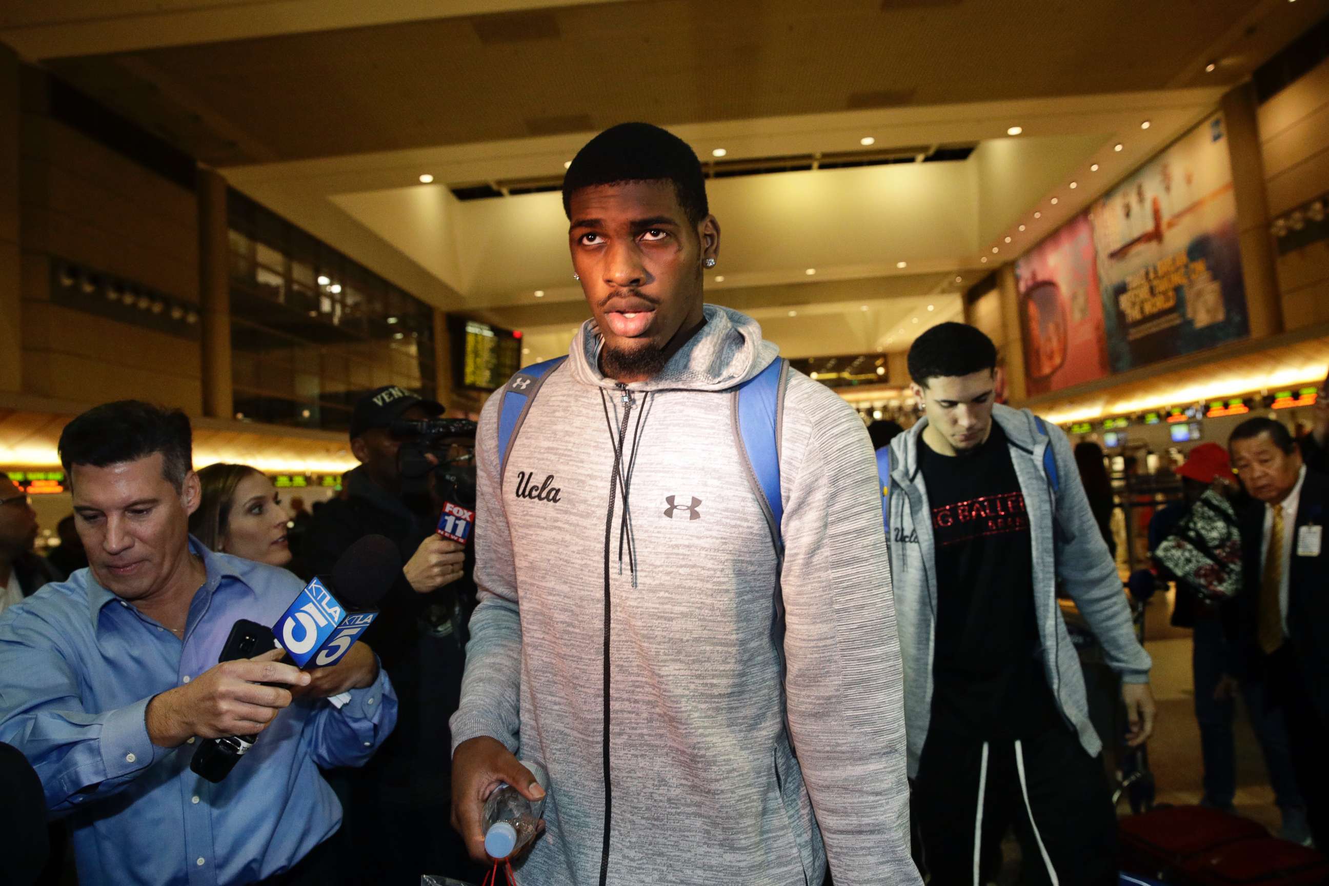 PHOTO: UCLA basketball players Cody Riley, center, and LiAngelo Ball, background right, are followed by the media as they leave Los Angeles International Airport, Nov. 14, 2017, in Los Angeles. 