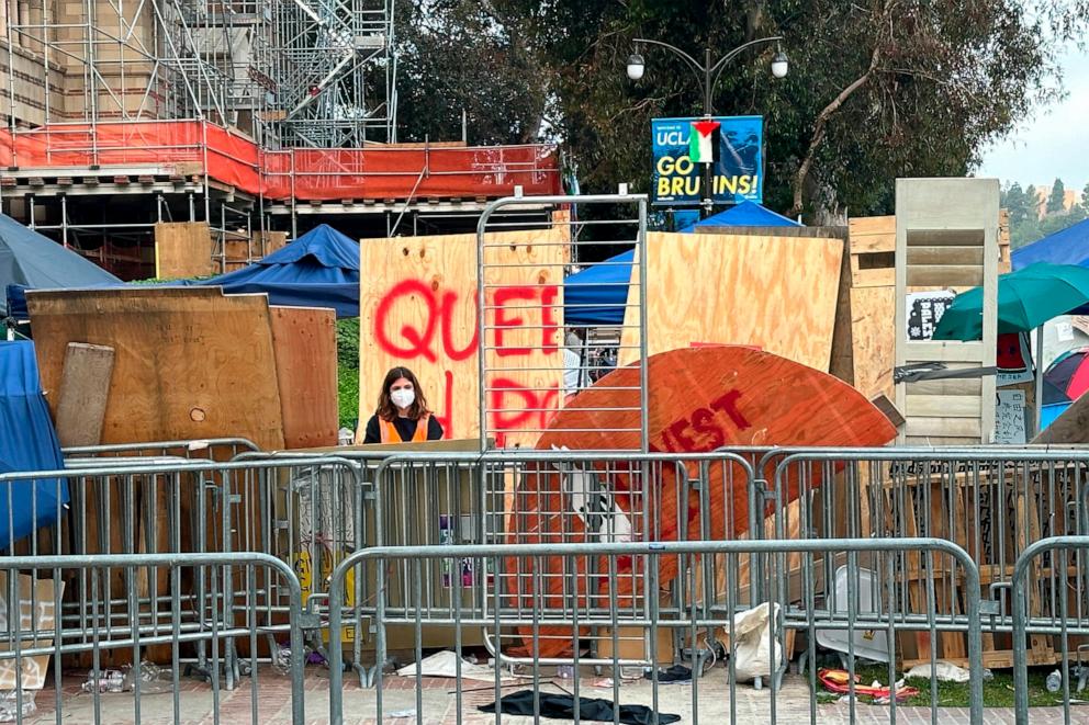PHOTO: A demonstrator stands in front of barricades set up to protect an encampment on the UCLA campus Wednesday, May 1, 2024, in Los Angeles. Dueling groups of protesters clashed early Wednesday.