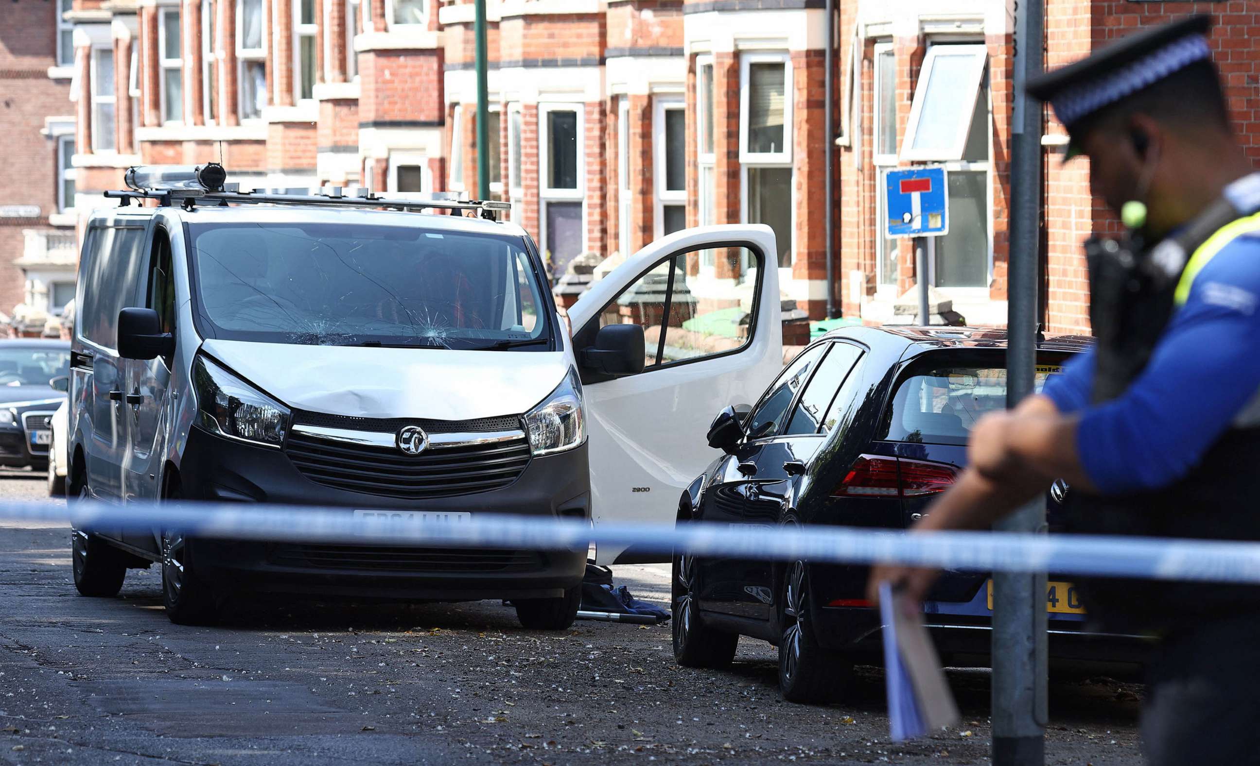 PHOTO: A police officer stands on duty by a white van with a shattered windscreen, inside a cordon on Bentinck Road in Nottingham, central England, during a 'major incident' in which three people have been found dead.