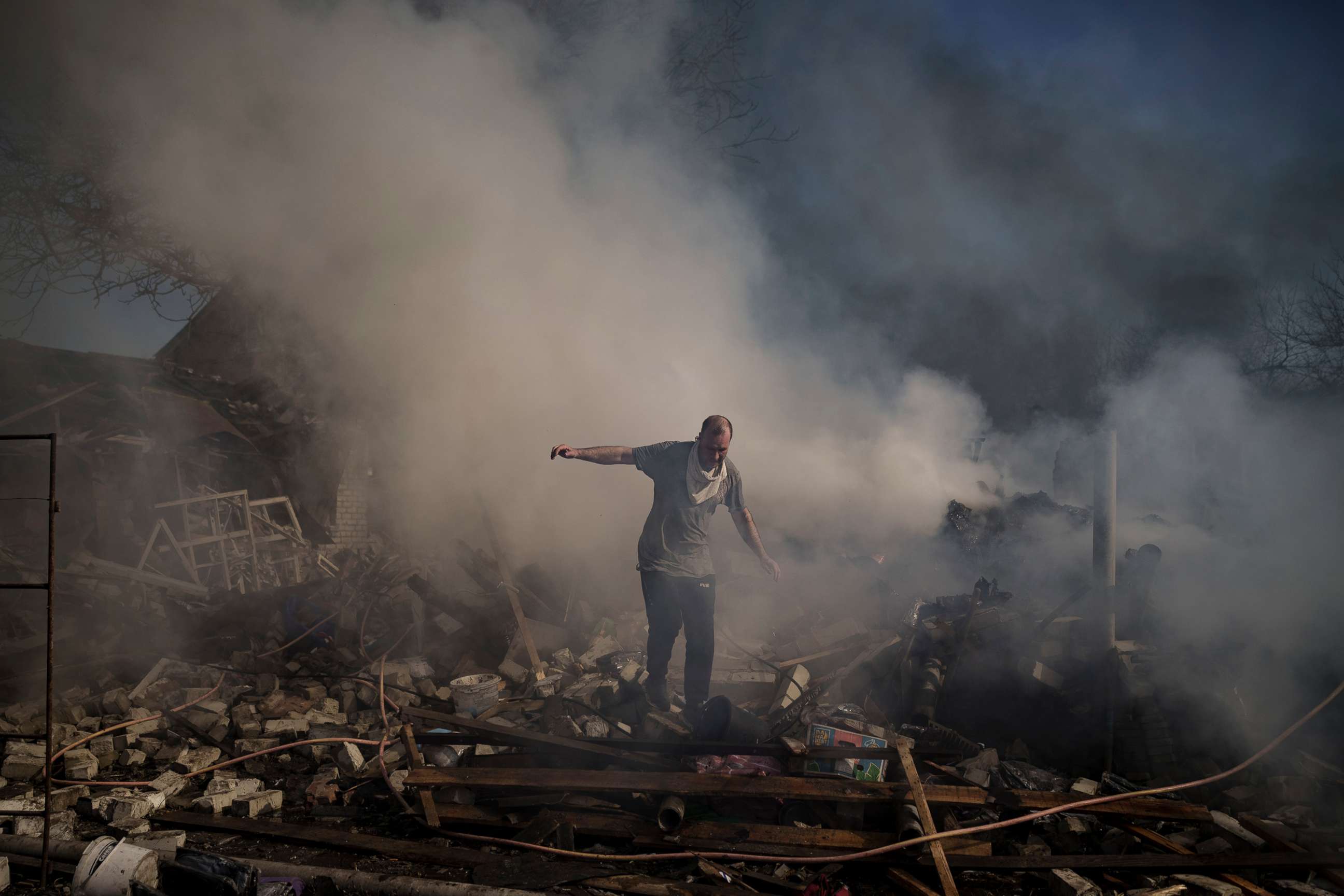 PHOTO: A man walks on the debris of a burning house, destroyed after a Russian attack in Kharkiv, Ukraine, March 24, 2022. 