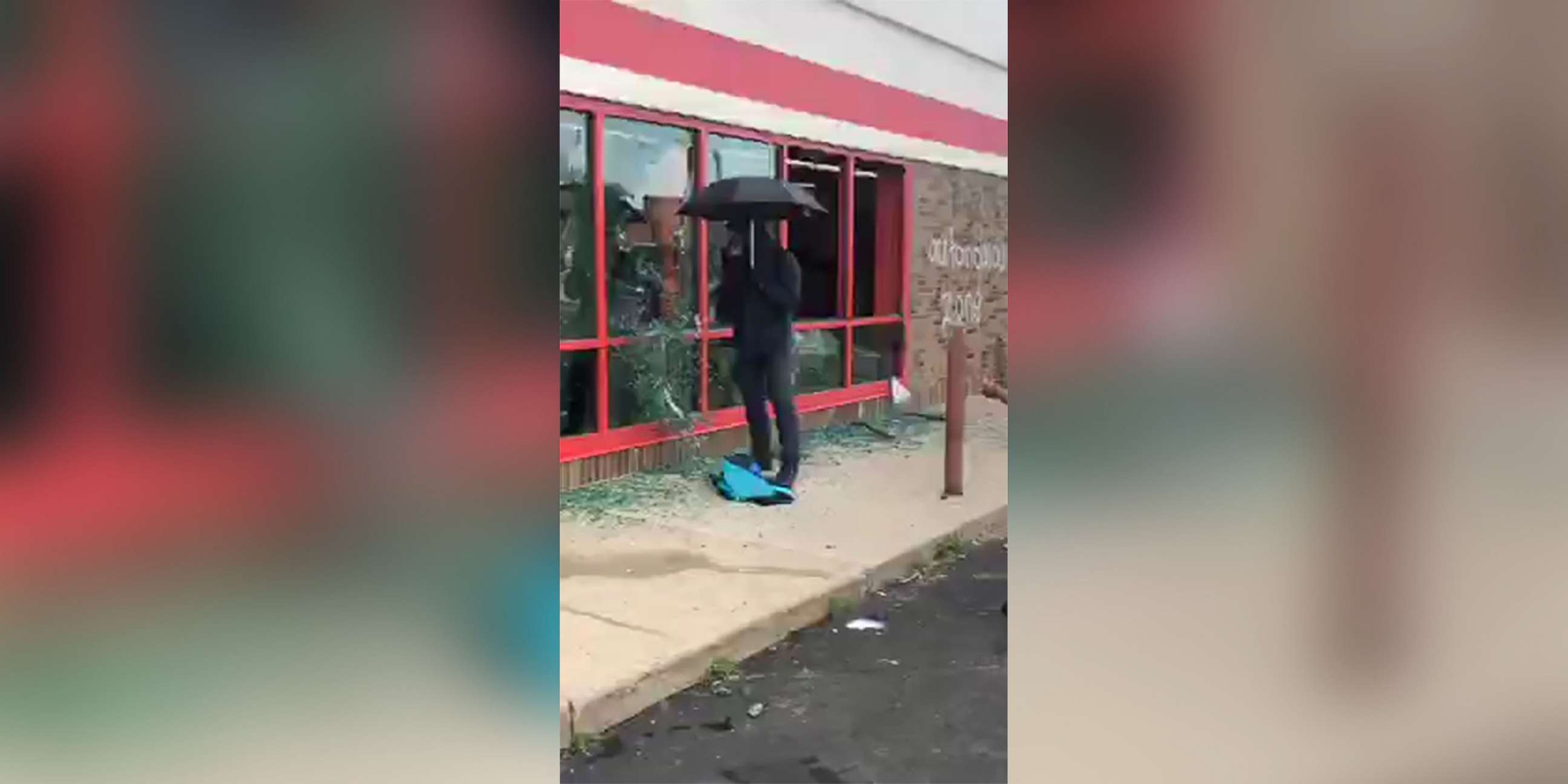 PHOTO: A man carrying an umbrella smashes windows at a store in Minneapolis, during protests following the death of George Floyd in May 2020.