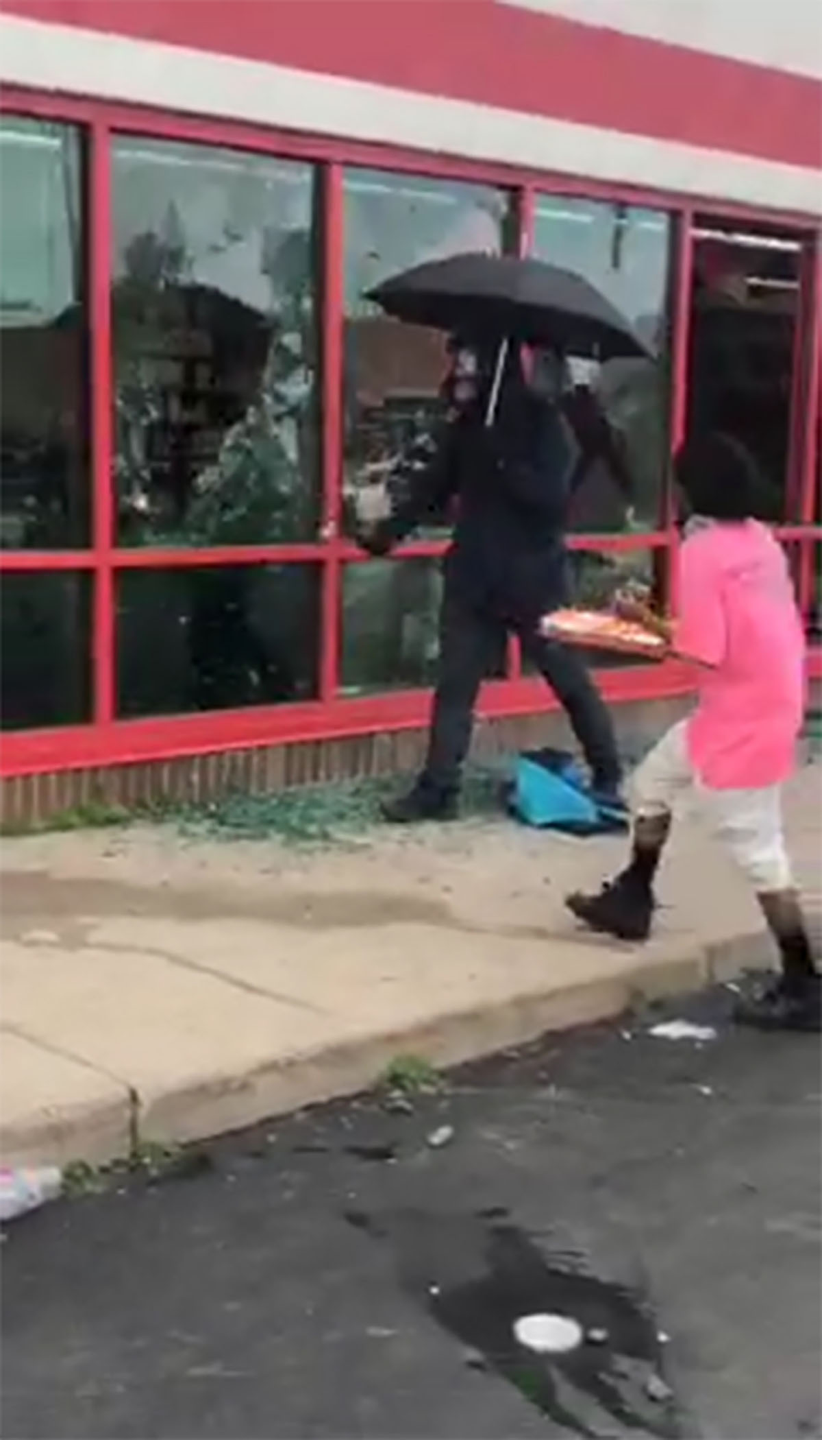 PHOTO: A man carrying an umbrella smashes windows at a store in Minneapolis, during protests following the death of George Floyd in May 2020.