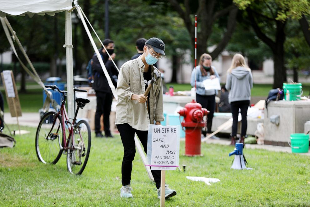 PHOTO: A member of the Graduate Employees' Organization Local 3550 stakes a sign into the ground in protest on the University of Michigan campus in Ann Arbor, Mich., Sept. 11, 2020. 