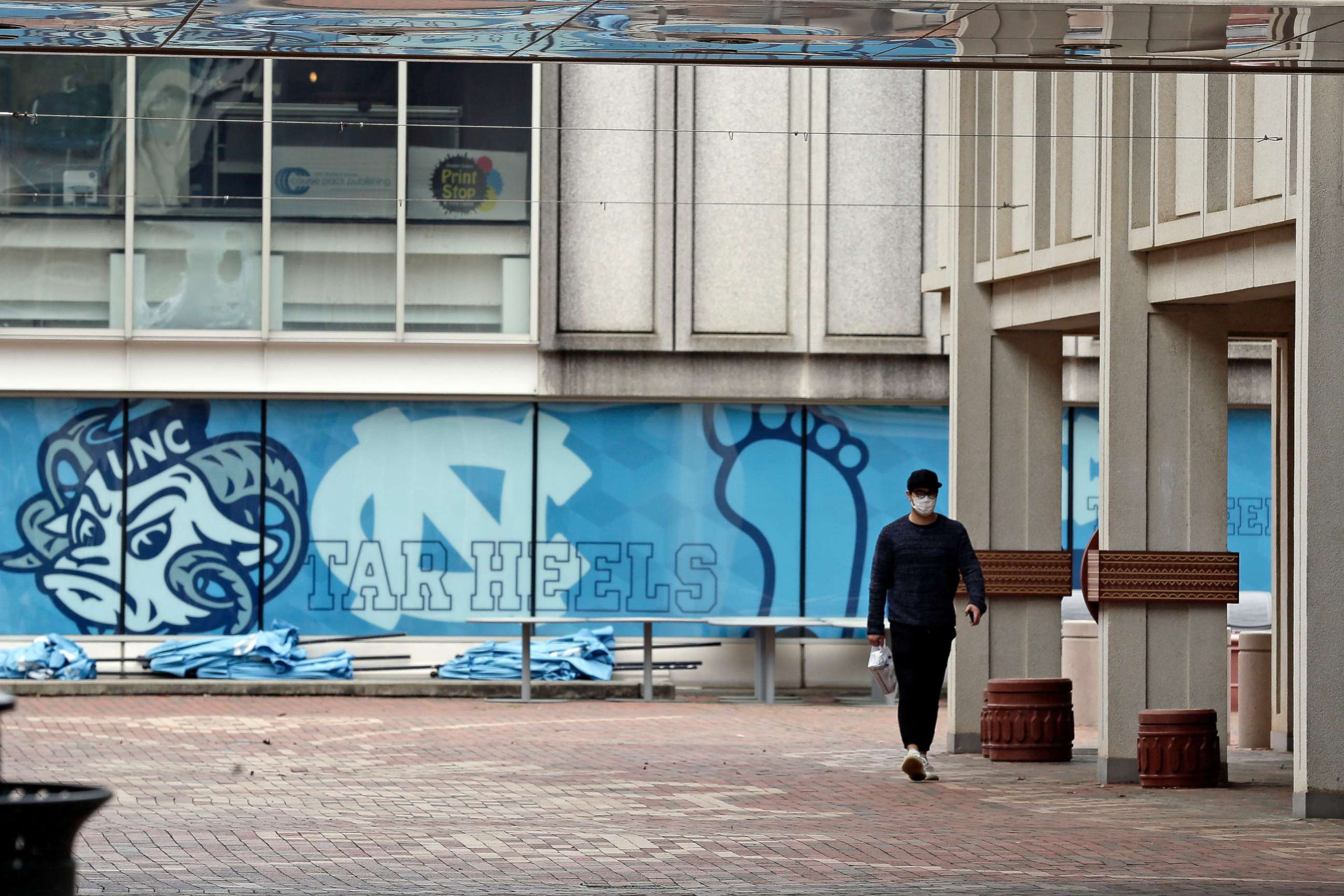 PHOTO: In this March 18, 2020 file photo, a pedestrian walks through campus at the University of North Carolina in Chapel Hill, N.C.