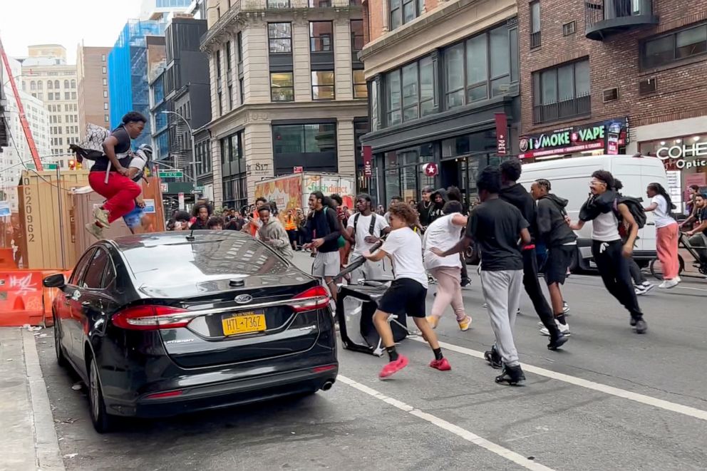 PHOTO: A man jumps on a car as a crowd runs through the street on Broadway near Union Square, Aug. 4, 2023, in New York.