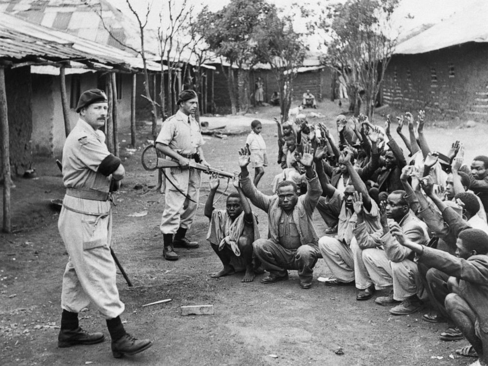 PHOTO: British policemen hold men from the village of Kariobangi at gunpoint while their huts are searched for evidence that they participated in the Mau Mau Rebellion of 1952.