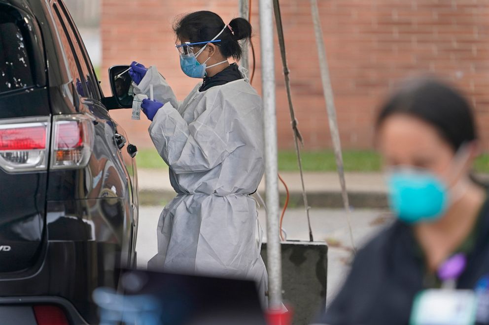 PHOTO: Medical personnel prepare to administer a COVID-19 swab at a drive-through testing site in Lawrence, N.Y., Oct. 21, 2020.