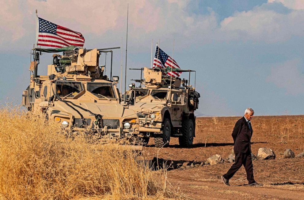 PHOTO: A Syrian man walks on as U.S. armoured vehicles patrol the northeastern town of Qahtaniyah at the border with Turkey, Oct. 31, 2019.