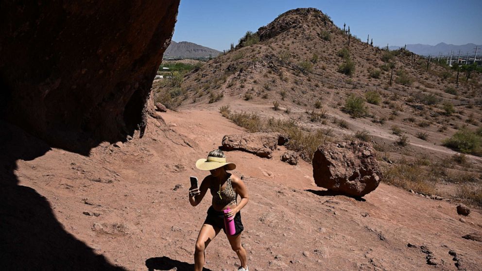 PHOTO: A visitor from Canada carries water as he hikes the Hole In The Rock trail during a record heat wave in Phoenix, Arizona on July 19, 2023.