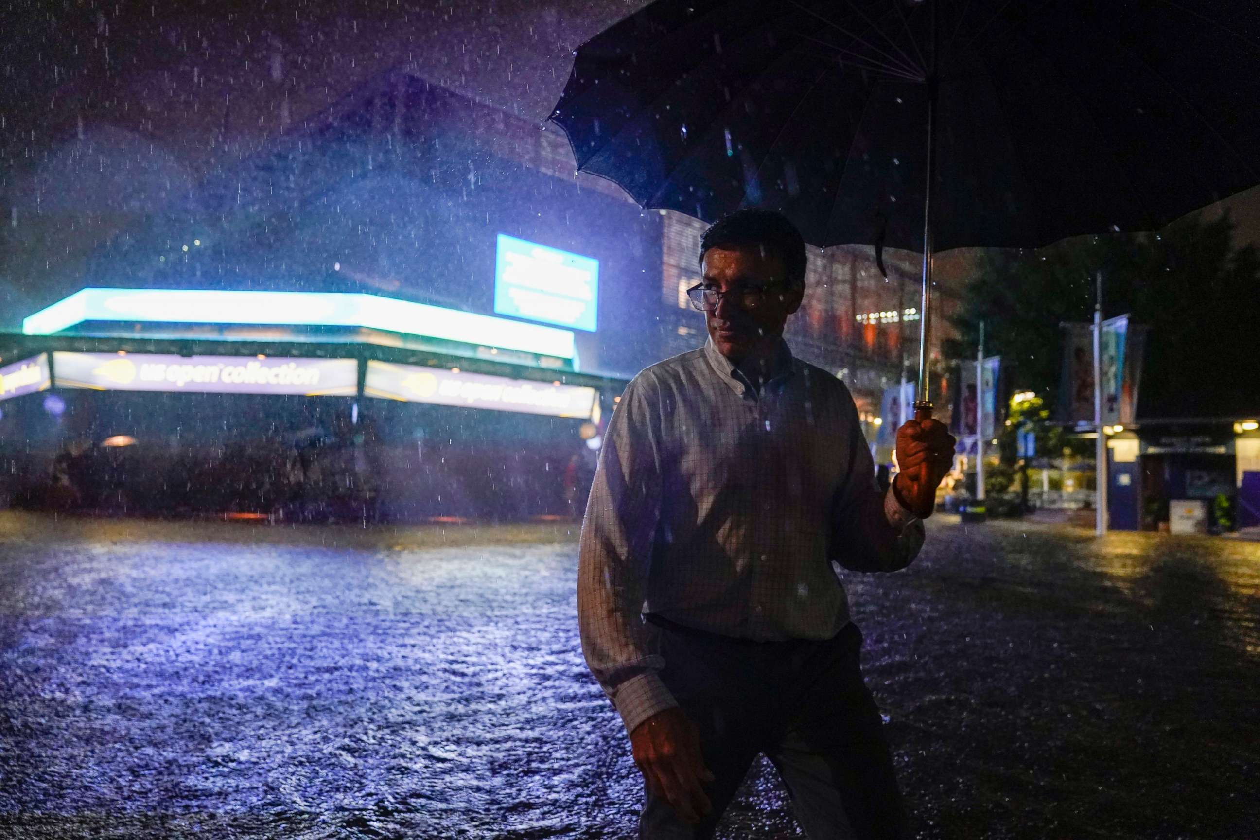 PHOTO: Sep 1, 2021; Flushing, NY, USA; A spectator walks through the flooded pavilion in front of Louis Armstrong Stadium on day three of the 2021 U.S. Open tennis tournament at USTA Billie Jean King National Tennis Center.