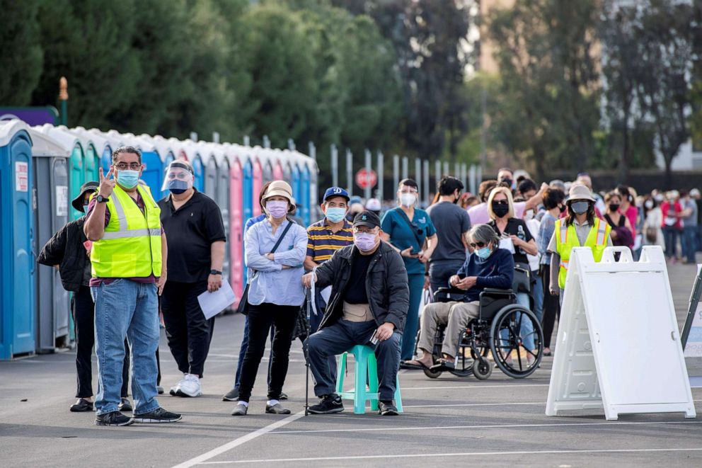 PHOTO: People wait in line in a Disneyland parking lot to receive Covid-19 vaccines on the opening day of the Disneyland Covid-19 vaccination "super Point-of-Dispensing" (POD) site, in Anaheim, Calif.
