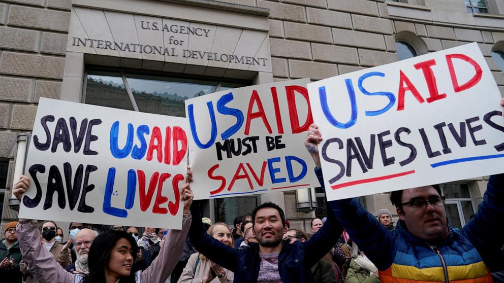 PHOTO: People hold placards as the USAID building sits closed to employees after a memo was issued advising agency personnel to work remotely, in Washington, Feb. 3, 2025.