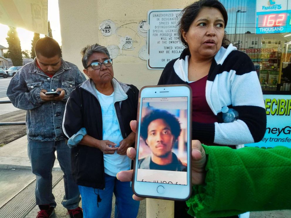 PHOTO: Neighbors react as they look at a cellphone picture of University of Southern California student Victor McElhaney, shown by a television reporter near the scene of a crime in Los Angeles, March 10, 2019.
