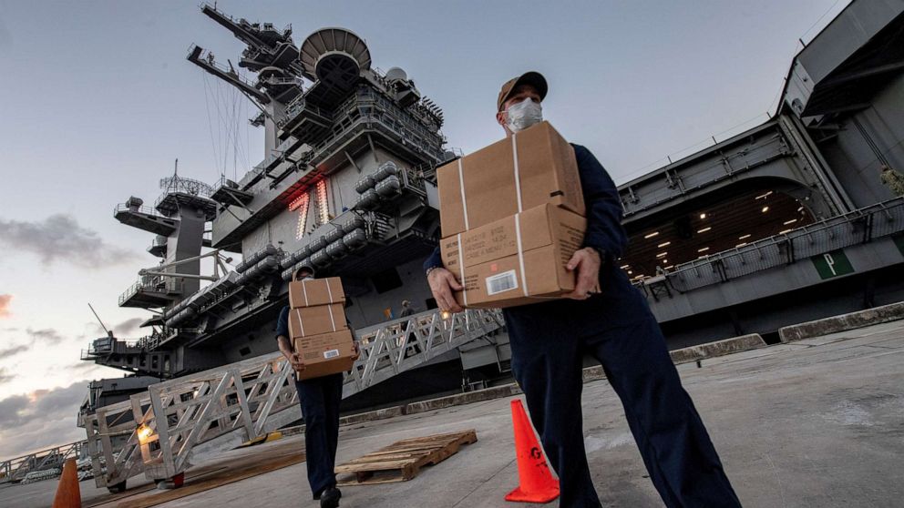 FILE PHOTO: U.S. Navy sailors assigned to the aircraft carrier USS Theodore Roosevelt move ready-to-eat meals (MREs) for quarantined sailors at Naval Base Guam on April 7, 2020.