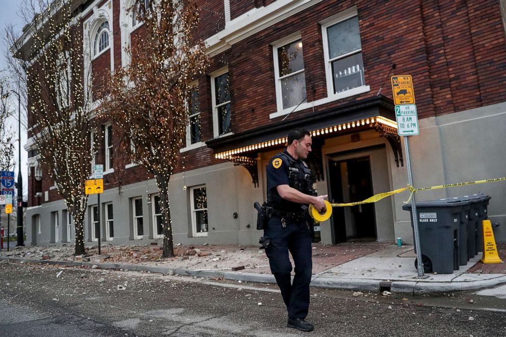 PHOTO: Salt Lake City Police Office Henry Vadnais strings up police tape around fallen bricks outside a building after an earthquake in Salt Lake City on Wednesday, March 18, 2020.