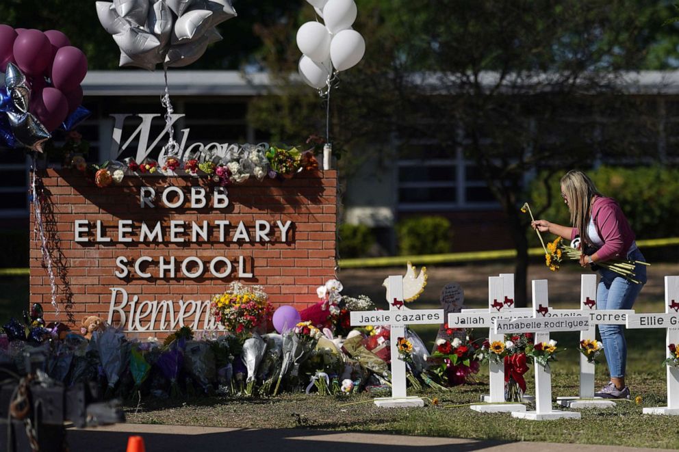 PHOTO: People drop off flowers at a makeshift memorial outside the Robb Elementary School, May 26, 2022, in Uvalde, Texas.