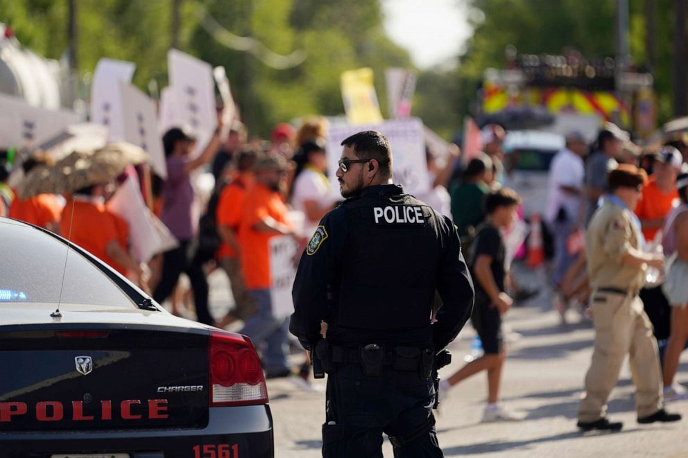 A Uvalde Police Department officer watches as family and friends of those killed and injured in the school shooting at Robb Elementary take part in a protest march and rally, Sunday, July 10, 2022, in Uvalde, Texas.