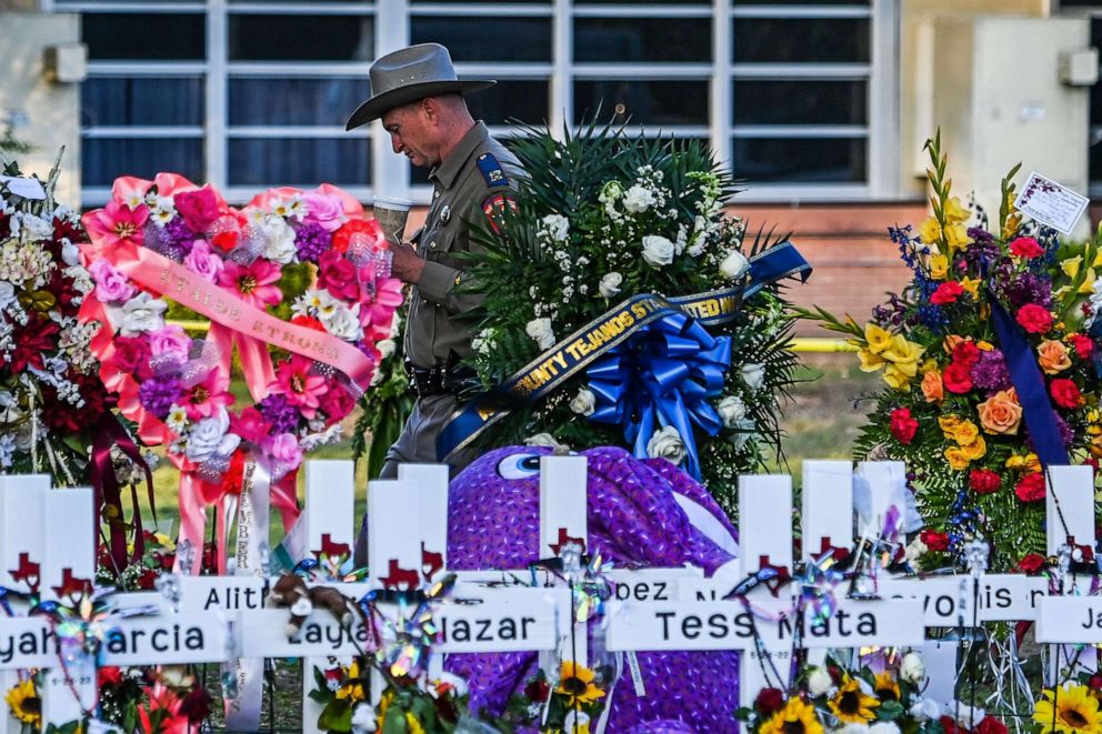 PHOTO: A police officer stands near the makeshift memorial outside Robb Elementary School in Uvalde, Texas, May 28, 2022. 