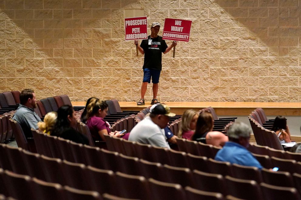 PHOTO: Michael Brown holds protest signs during a special meeting of the Board of Trustees of Uvalde Consolidated Independent School District where parents addressed last month's shooting at Robb Elementary School, on July 18, 2022, in Uvalde, Texas.
