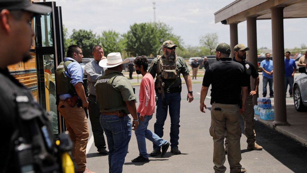 PHOTO : Des enfants montent dans un bus scolaire alors que les forces de l'ordre surveillent la scène d'une fusillade présumée près de l'école élémentaire Robb à Uvalde, Texas, le 24 mai 2022.