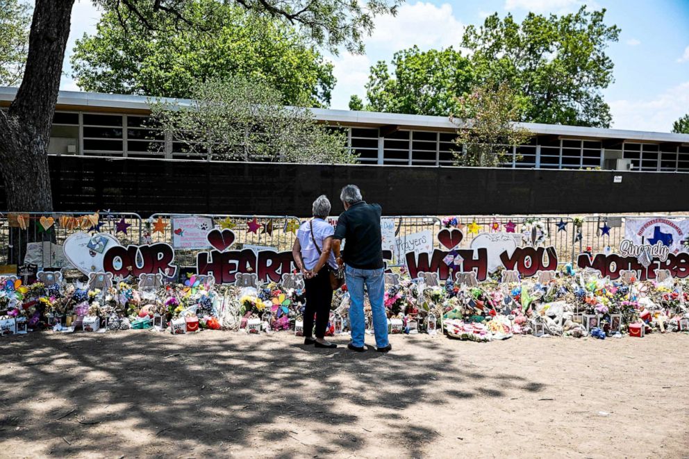 PHOTO: People visit a makeshift memorial to the victims of a shooting at Robb Elementary School which is now surrounded by fencing, in Uvalde, Texas, June 30, 2022. 