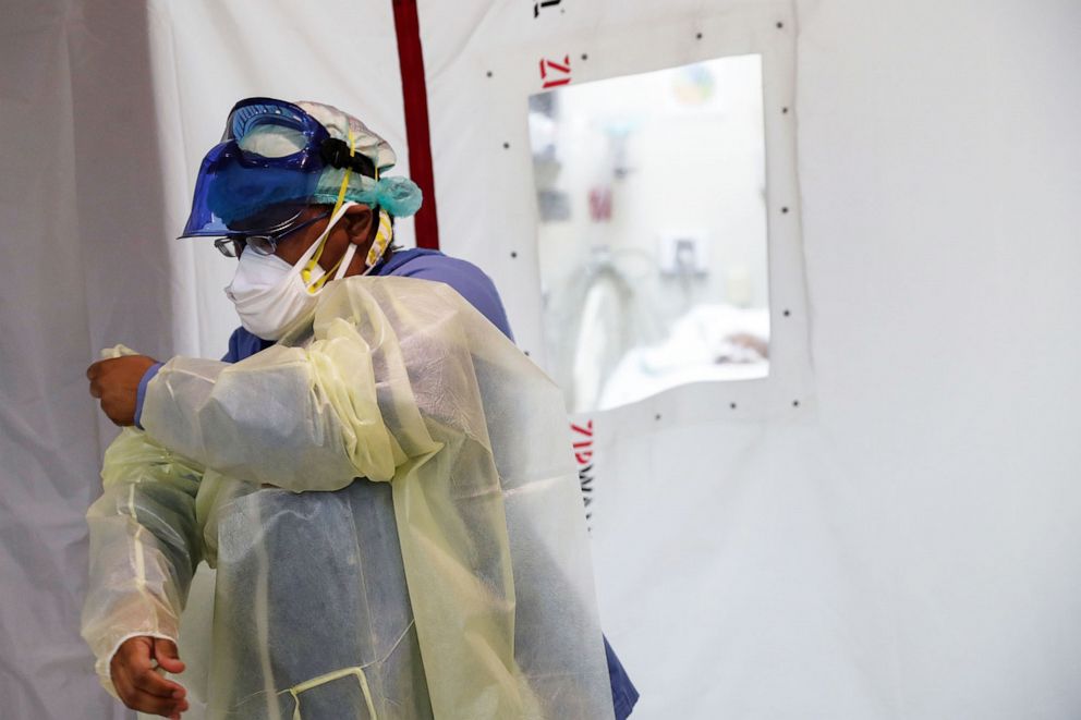 PHOTO: Registered nurse Tamara Jones dresses in Personal Protective Equipment (PPE) outside an isolation room in the intensive care unit at Roseland Community Hospital on the South Side of Chicago, Dec. 8, 2020.