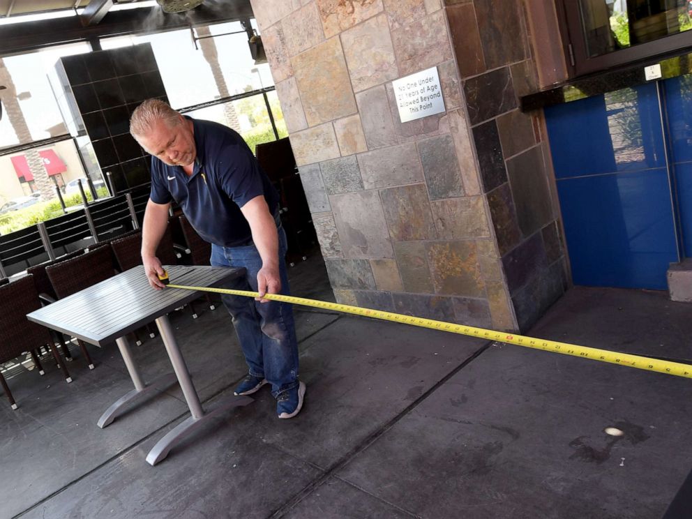 PHOTO: Maintenance contractor Tod Brandenburg measures six-foot distances between tables as he sets up a patio area at Kona Grill in Boca Park Fashion Village, May 9, 2020, in Las Vegas, Nevada.