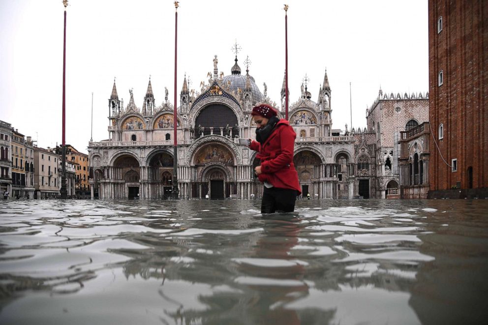 PHOTO: A woman crosses the flooded St. Marks square by St. Marks Basilica after an exceptional overnight Alta Acqua high tide water level, Nov. 13, 2019 in Venice. 