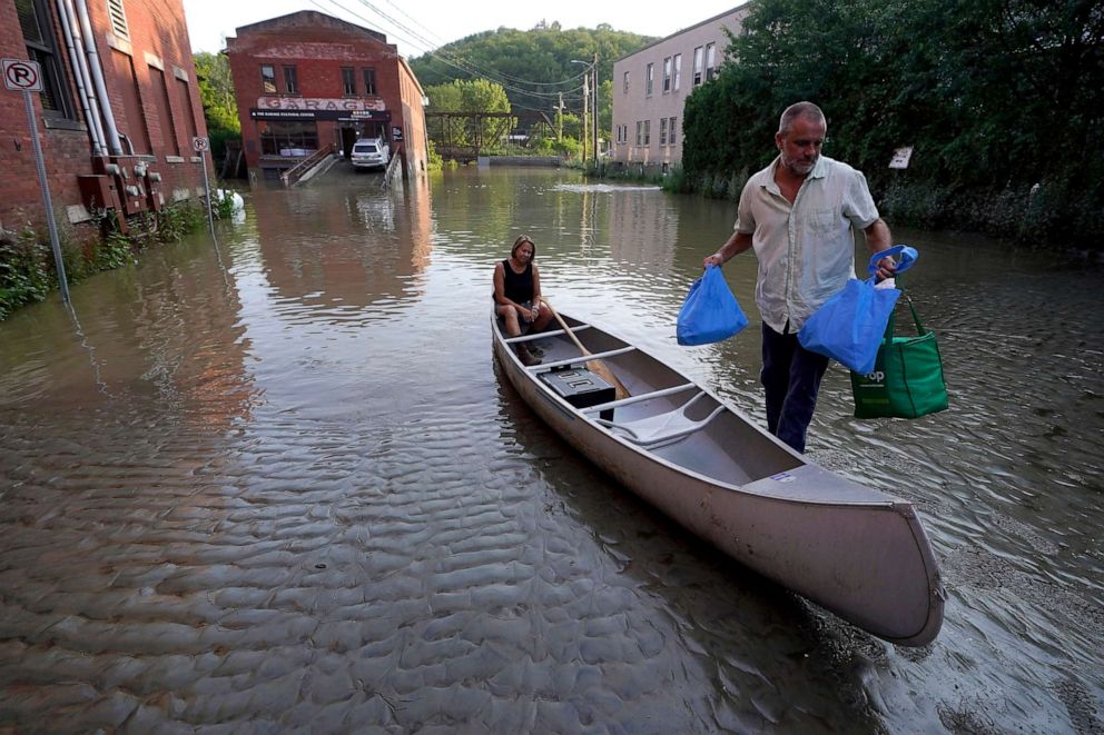PHOTO: Jodi Kelly, seated center, practice manager at Stonecliff Veterinary Surgical Center, behind, and her husband Veterinarian Dan Kelly, right, use a canoe to remove surgical supplies from the flood damaged center, July 11, 2023, in Montpelier, Vt.