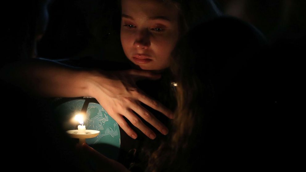 PHOTO: A young girl clutches a friend during candlelight vigil for victims of the mass shooting at Marjory Stoneman Douglas High School yesterday, at Pine Trail Park, Feb. 15, 2018 in Parkland, Fla. 