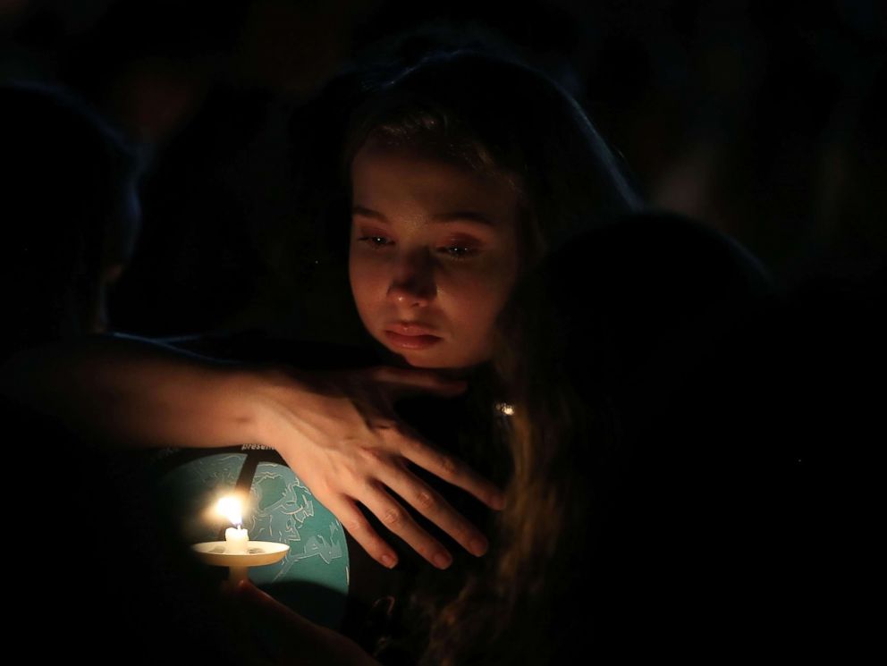 PHOTO: A young girl clutches a friend during candlelight vigil for victims of the mass shooting at Marjory Stoneman Douglas High School yesterday, at Pine Trail Park, Feb. 15, 2018 in Parkland, Fla. 