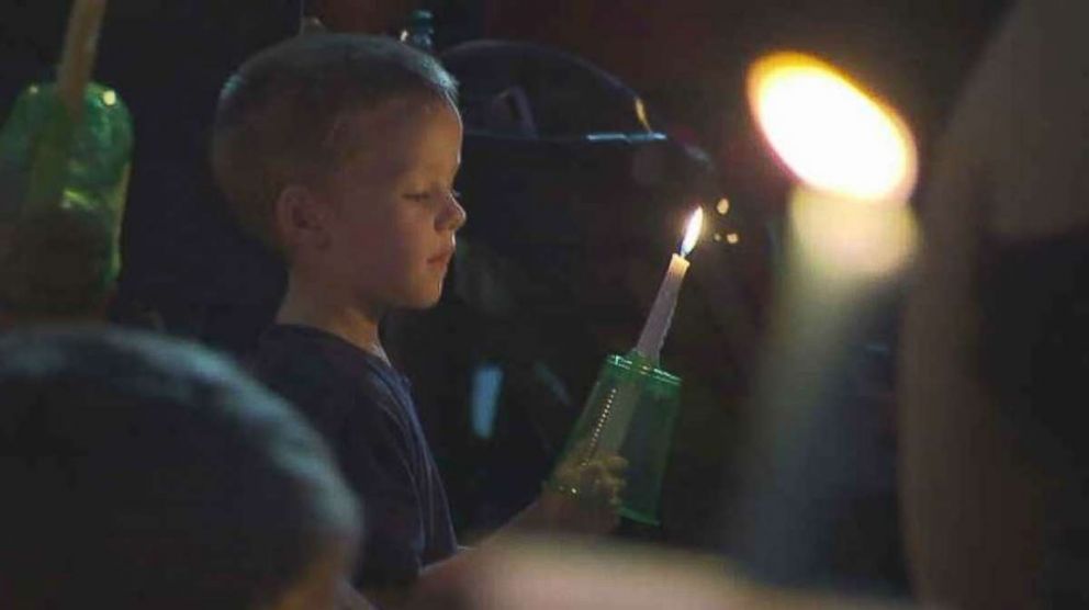 A child holds a candle at a vigil for the 17 people killed the previous day in a duck boat accident in Branson, Missouri, on Friday, July 20, 2018.