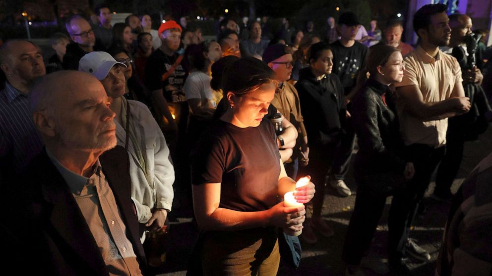 PHOTO: Marie Crane, center, holds a candle during a vigil in Tower Grove Park for the victims of a school shooting at Central Visual & Performing Arts High School in St. Louis, Oct. 24, 2022.