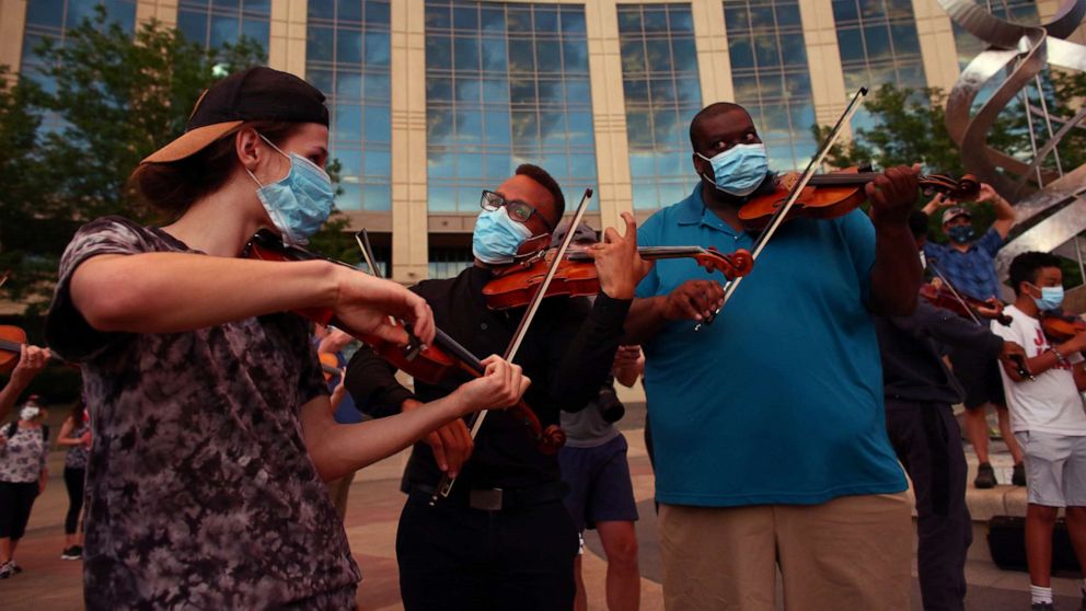 PHOTO: Protesters play along with other violinists to honor Elijah McClain, who, when alive, would play his violin at animal shelters because he thought the kittens were lonely, during a vigil in Aurora, Colorado, June 27, 2020.