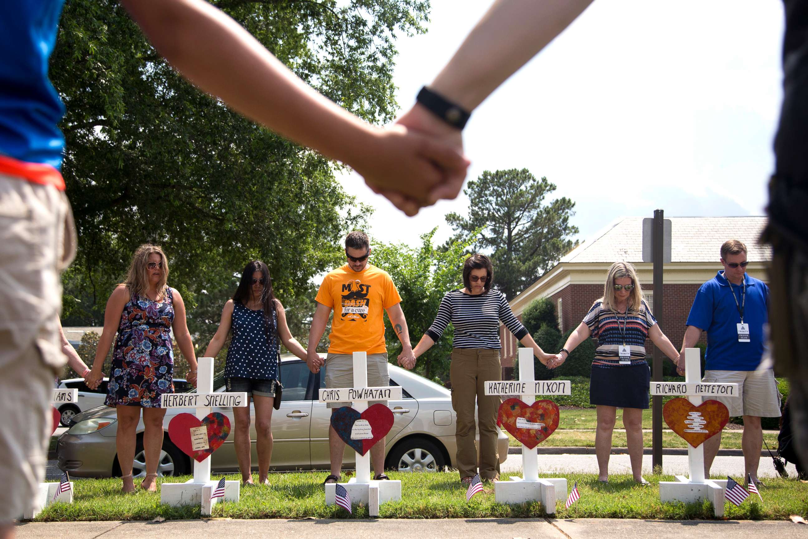 PHOTO: Community members hold hands and pray around the 12 crosses at the memorial located by Building 11 of the Municipal Center, June 2, 2019, in Virginia Beach, Va. 