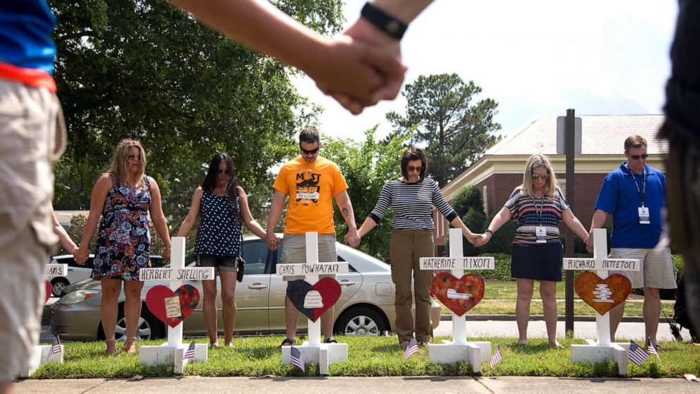 PHOTO: Community members hold hands and pray around the 12 crosses at the memorial located by Building 11 of the Municipal Center, June 2, 2019, in Virginia Beach, Va. 