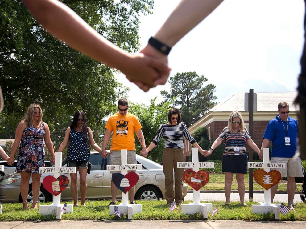 PHOTO: Community members hold hands and pray around the 12 crosses on the memorial near Building 11 of the Civic Center, June 2, 2019, in Virginia Beach, Virginia. 