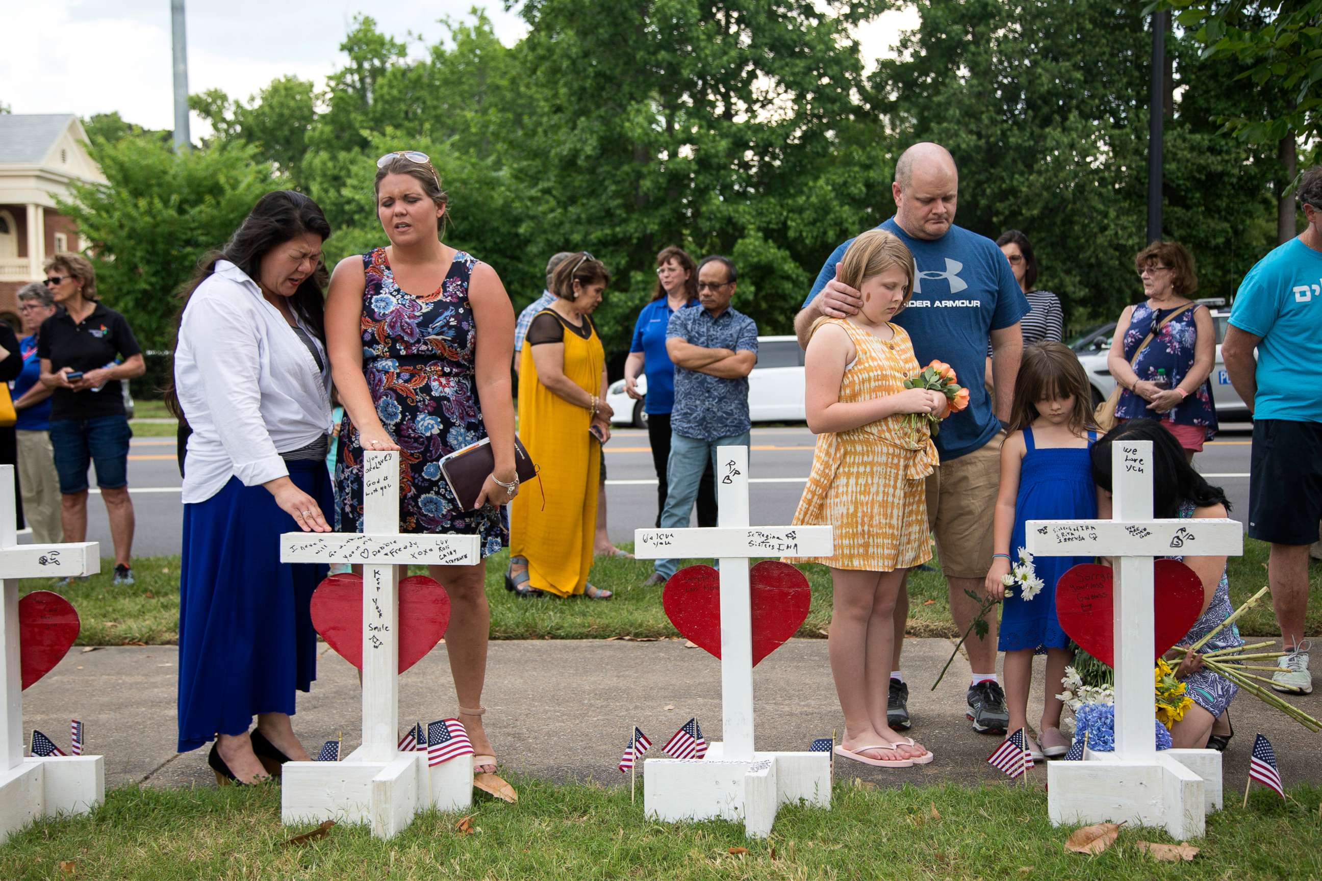 PHOTO: Christine Craig, left, and Brittany Perry, pray over each of the 12 crosses at the memorial located at the Virginia Beach Municipal Center, on June 2, 2019, in Virginia Beach, Va. 
