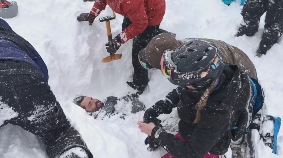 PHOTO: A man buried in snow after avalanche gets dug out by others at ski resort.