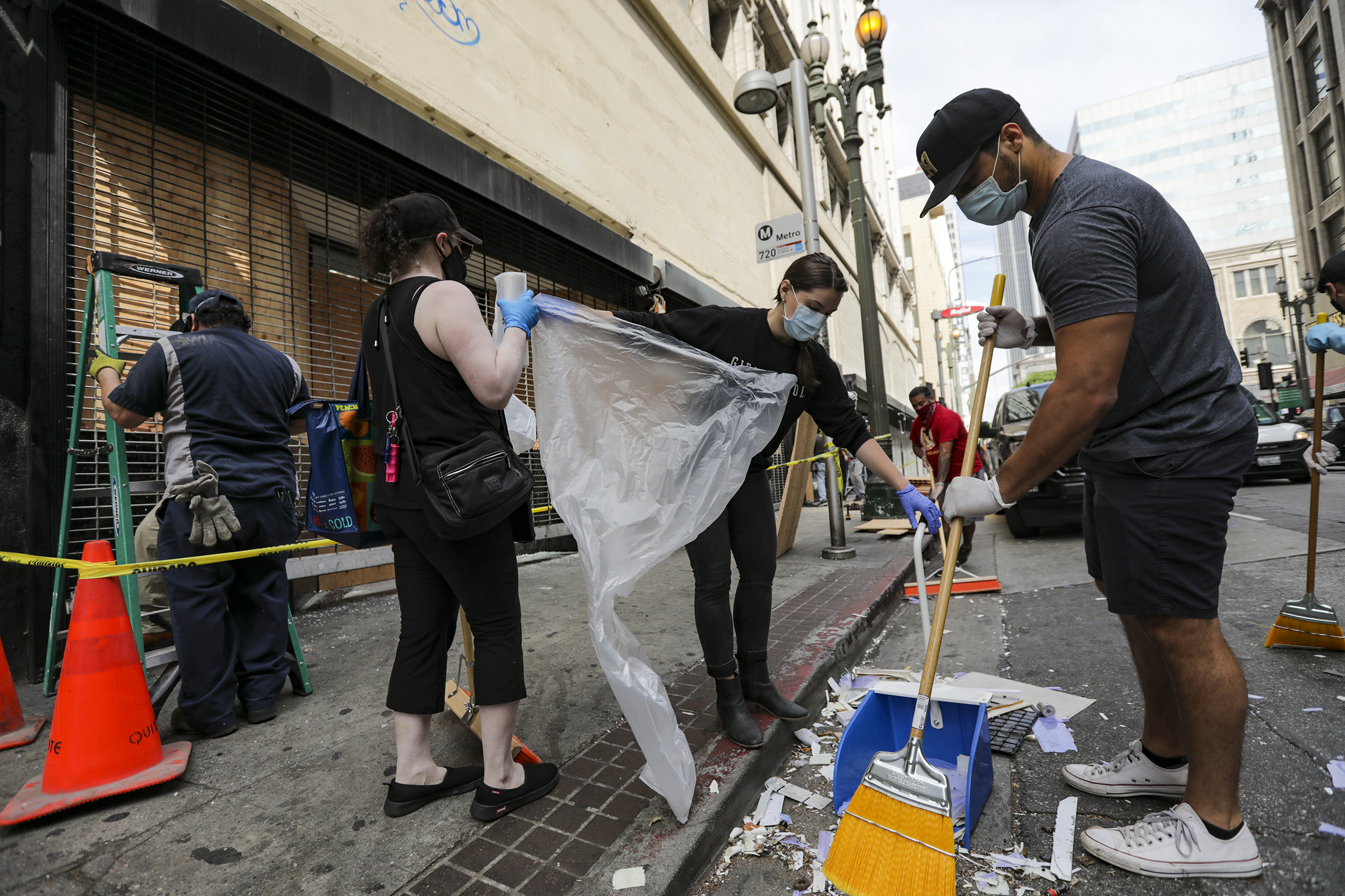 PHOTO: A group volunteers from DTLA Town Square help clean up the streets littered with broken glasses and trash after last night protest of the killing of George Floyd, May 30, 2020 in Los Angeles.