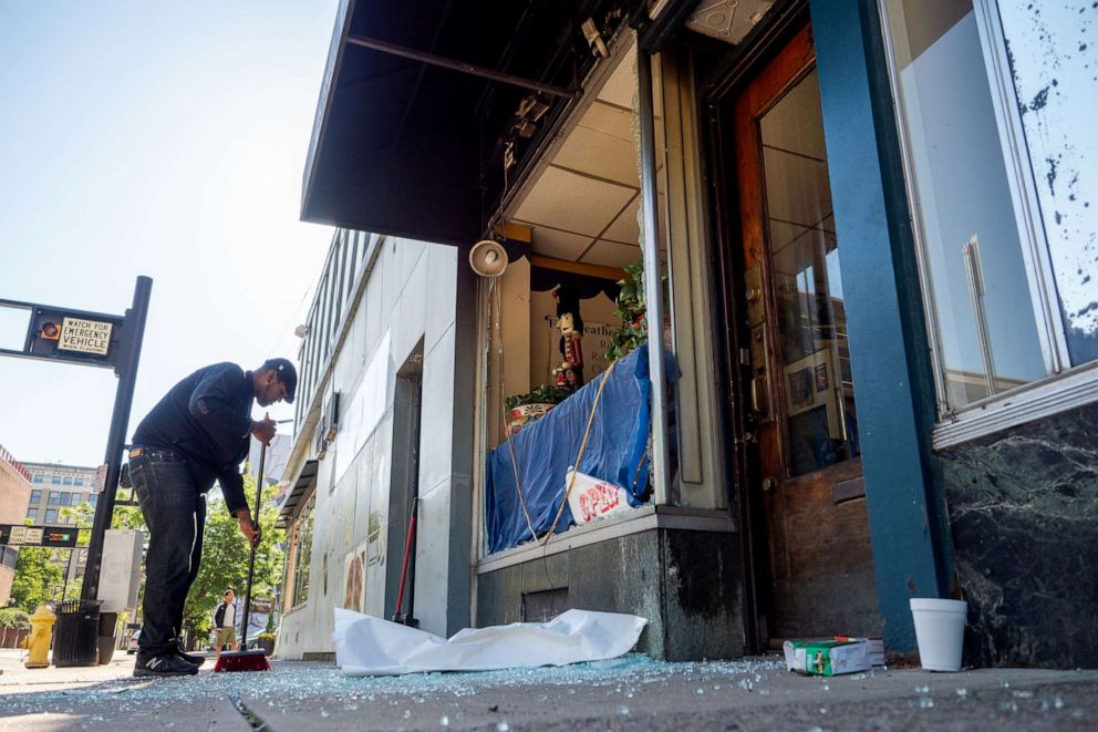 PHOTO: Volunteers clean up glass from a broken storefront window as protests over the death of George Floyd became violent resulting in damage and looting of several businesses in the Over-The-Rhine District, May 30, 2020, in Cincinnati.
