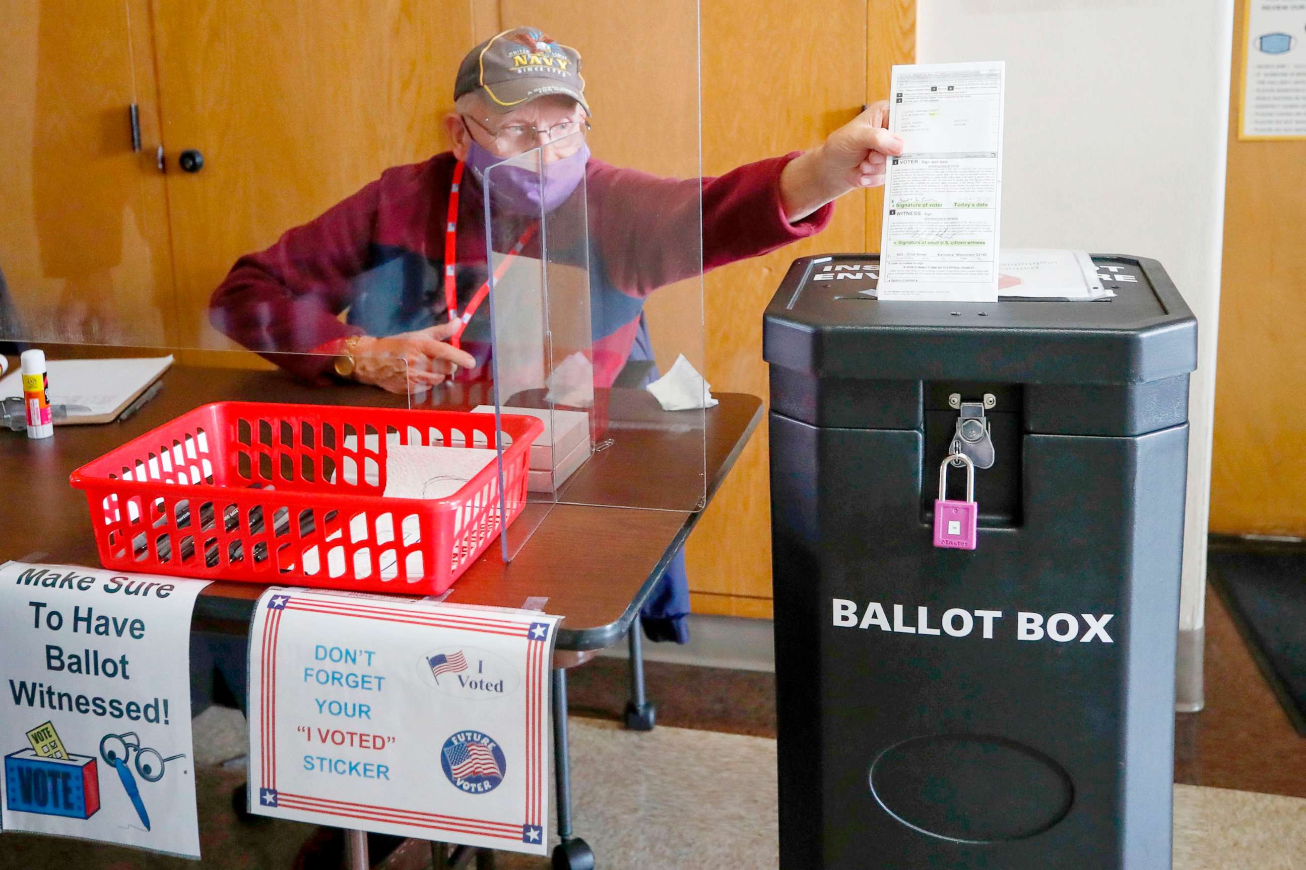 PHOTO: An election worker drops a voter's completed ballot into a ballot box inside City Hall on the first day of in-person early voting in Kenosha, Wisc., Oct. 20, 2020.