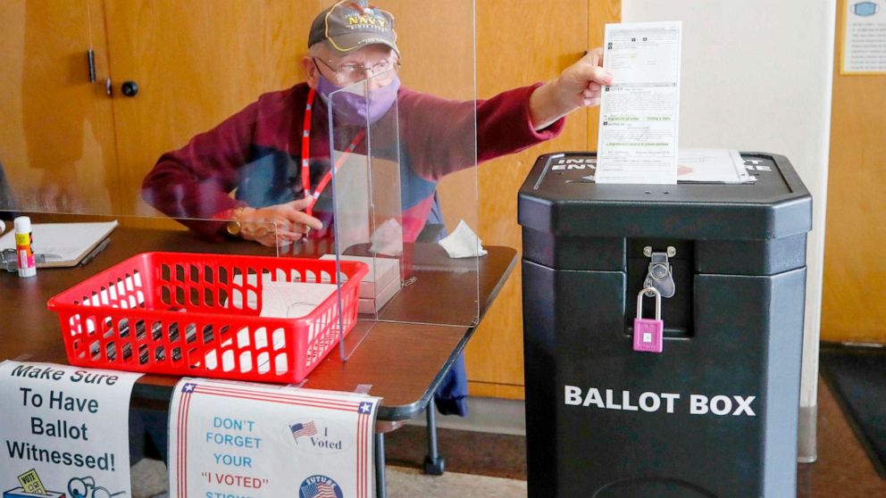 PHOTO: An election worker drops a voter's completed ballot into a ballot box inside City Hall on the first day of in-person early voting in Kenosha, Wisc., Oct. 20, 2020.